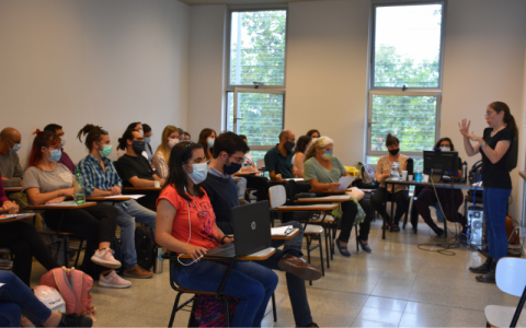 Fotografía: un grupo de estudiante sentados en un aula, con tapabocas escuchando una clase. A la derecha hay una interprete de Lengua de Señas Uruguaya