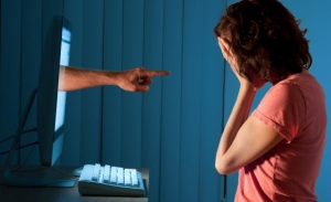 Fotografía de una mujer frente a una televisión. La mujer se tapa la cara con sus manos y una mano sale de la tv señalándola.