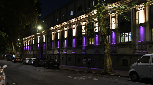 Fachada del edificio central de la Facultad de Psicología iluminada de color violeta