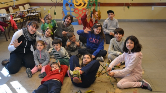 Fotografía de uno de los días en la que se ve a niñas y niños sonriendo a la cámara junto con tres de los recreadores.