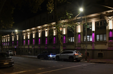 Vista nocturna de la fachada del edificio central de la Facultad de Psicología, iluminada en color violeta.