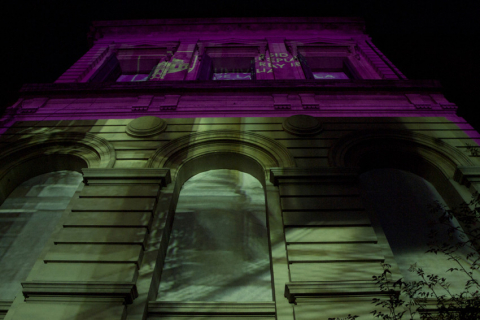 Fotografía de un sector de la fachada del edifico central de la Universidad con mapping sobre la misma.