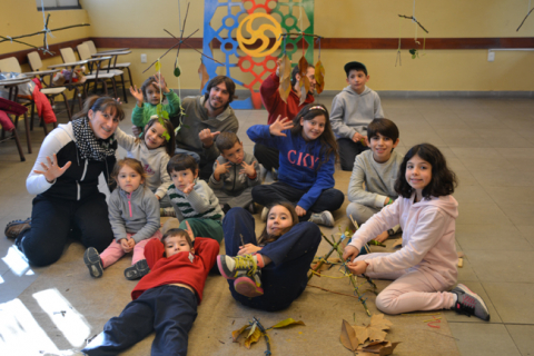 Fotografía de uno de los días en la que se ve a niñas y niños sonriendo a la cámara junto con tres de los recreadores.